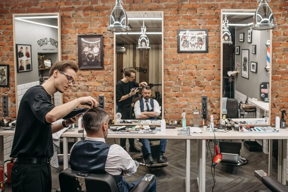 Interior da barbearia com espelhos e paredes de tijolo