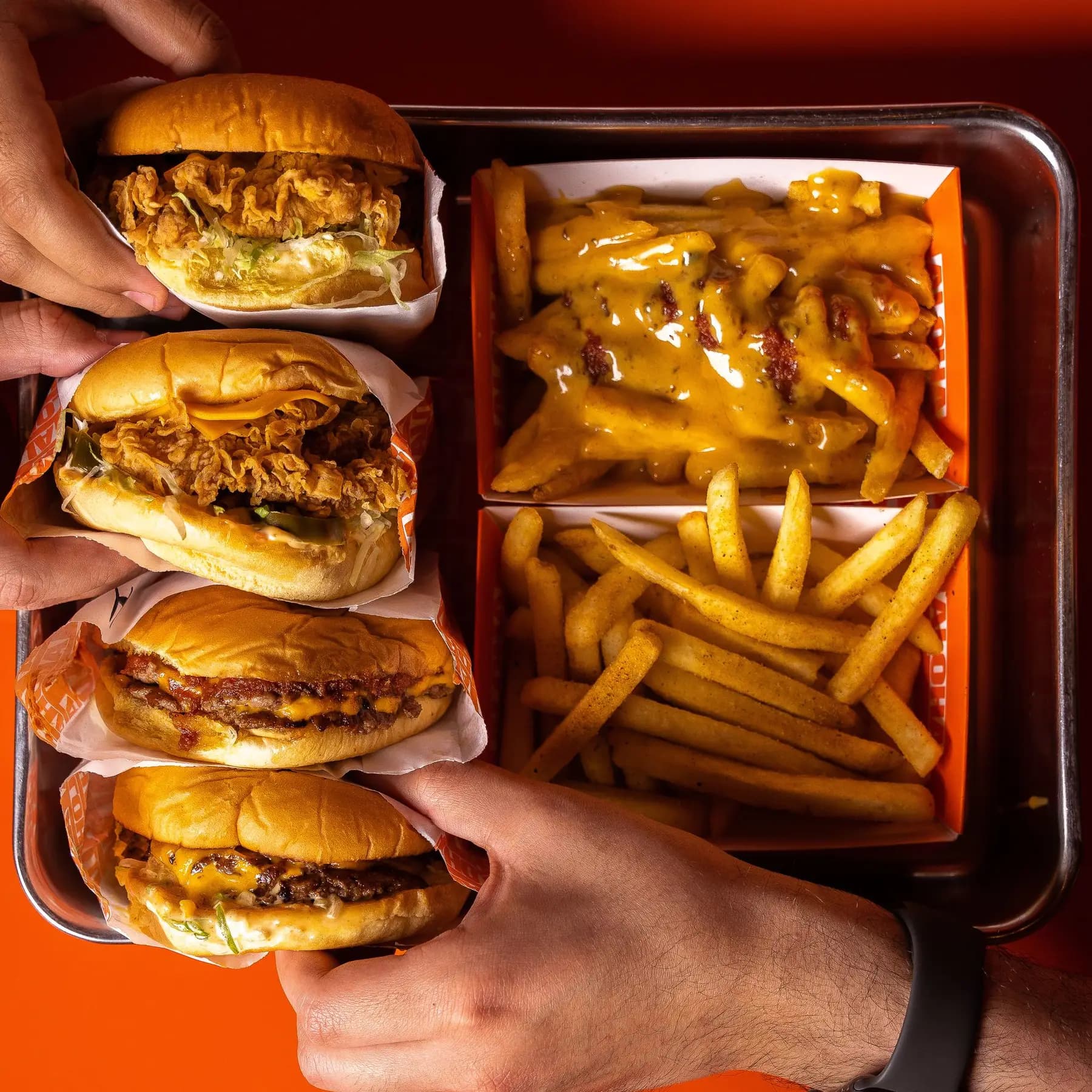 Tabuleiro com smash burgers e batatas fritas com queijo