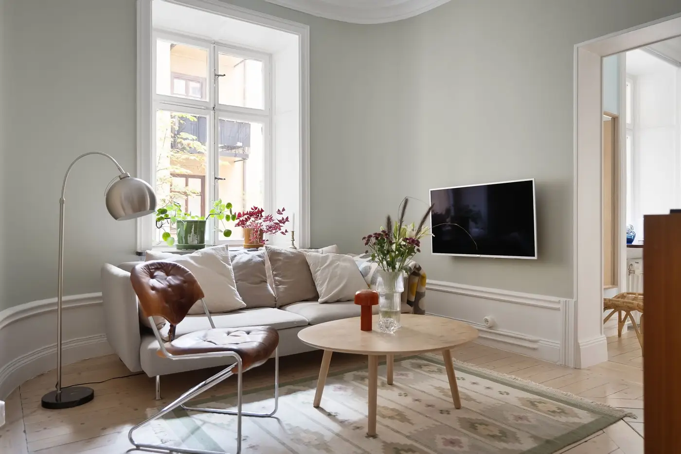 Sala clara com sofá branco e janelas altas
