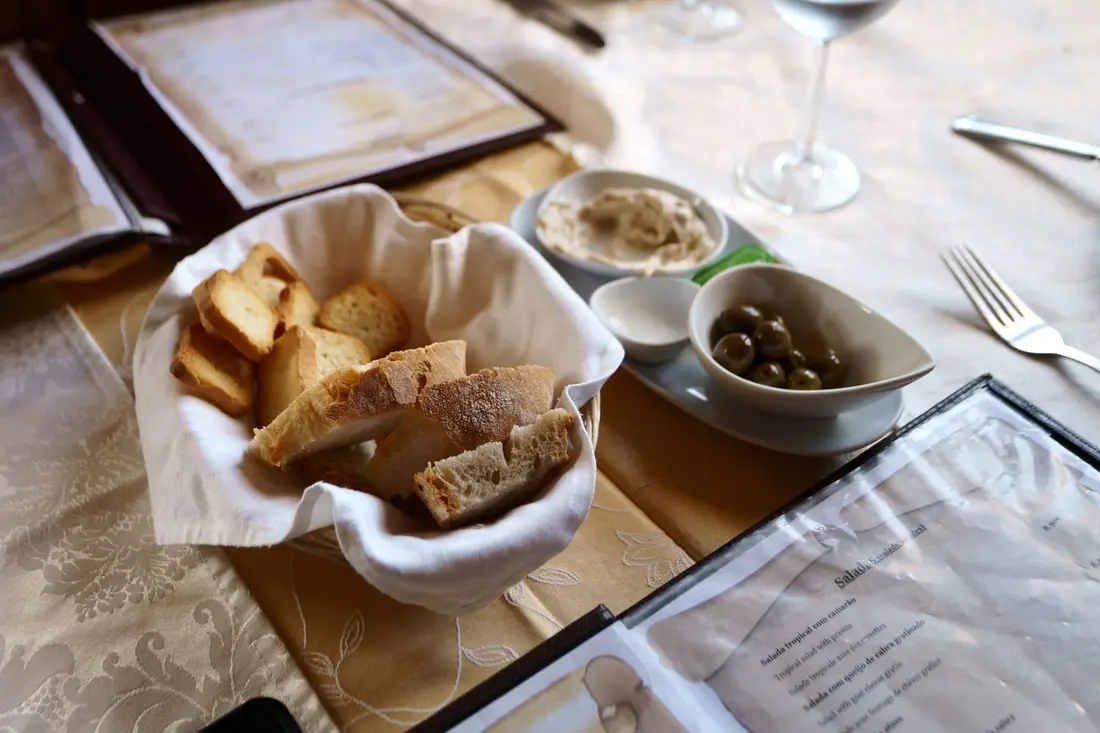 Pão, azeitonas e manteiga numa mesa posta