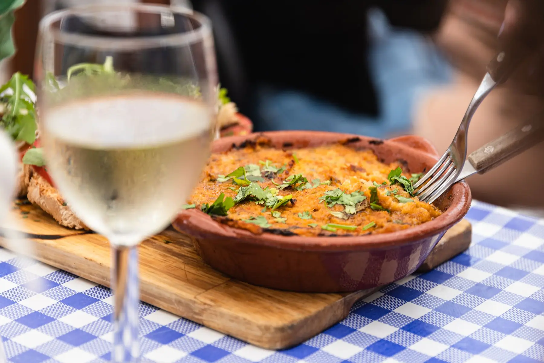 Prato de barro com comida tradicional e um copo de vinho branco
