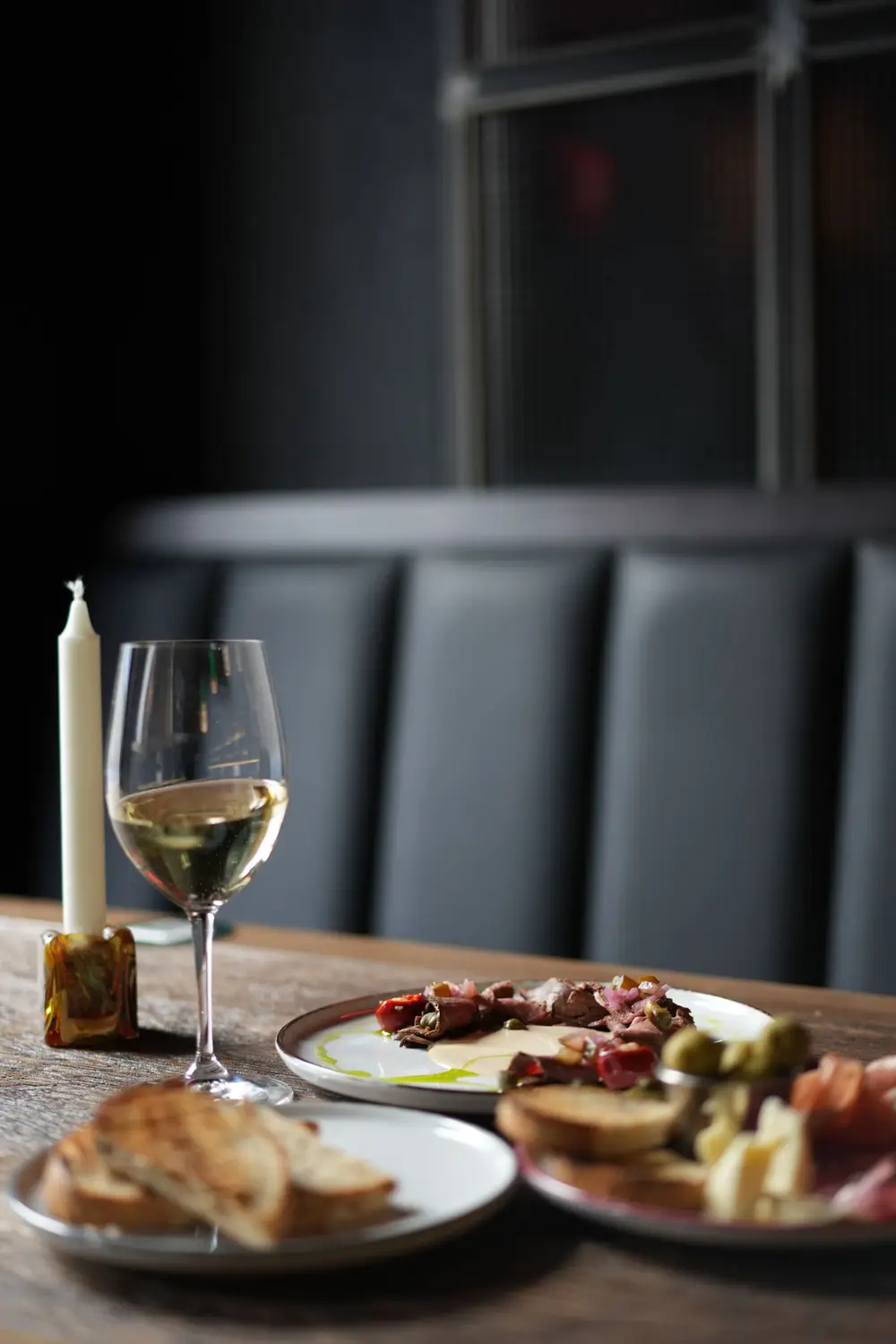 Mesa com vela acesa e um copo de vinho branco