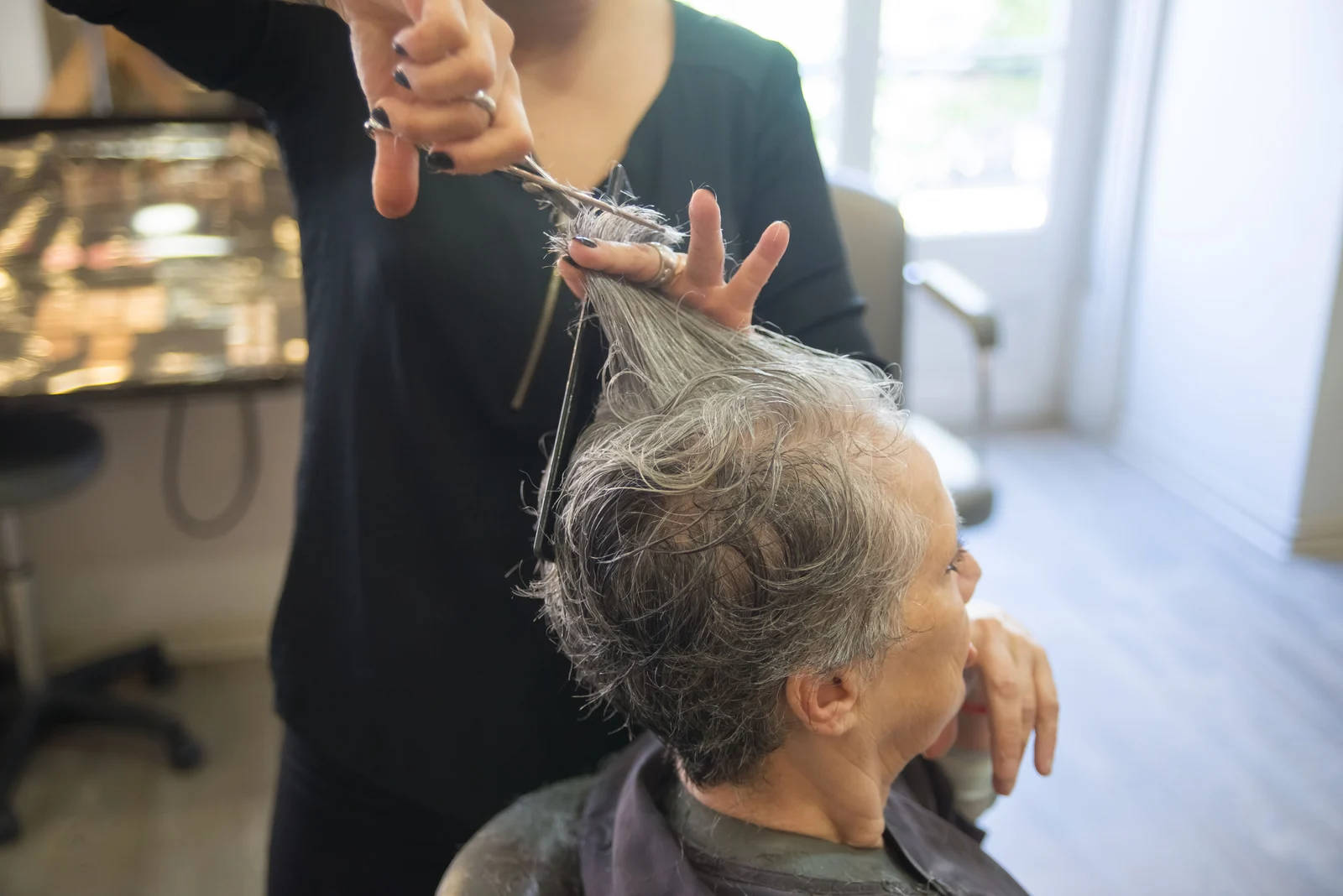 Senhora de cabelo branco a cortar o cabelo