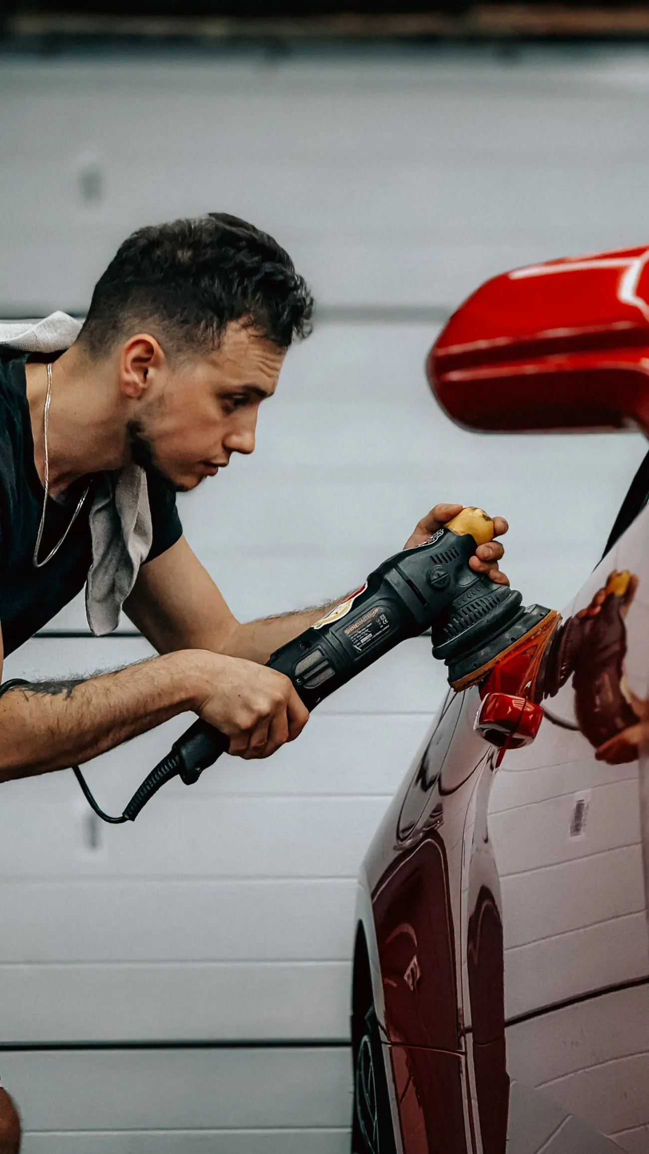 Homem a polir a pintura de um carro vermelho