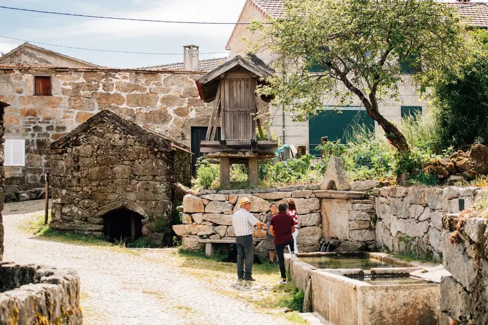 Rua de aldeia com casas de pedra e um espigueiro