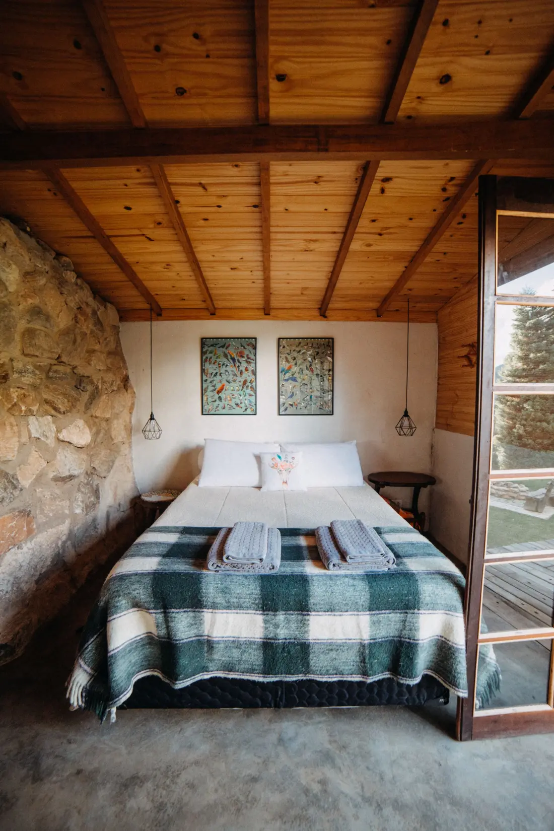 Quarto com parede de pedra, teto de madeira e janela aberta