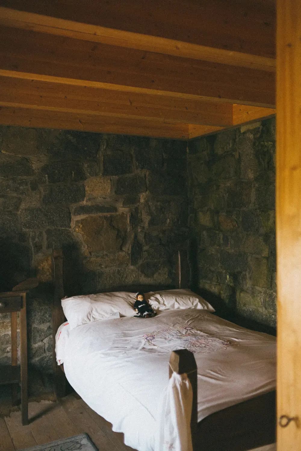 Quarto com paredes de pedra e cama branca