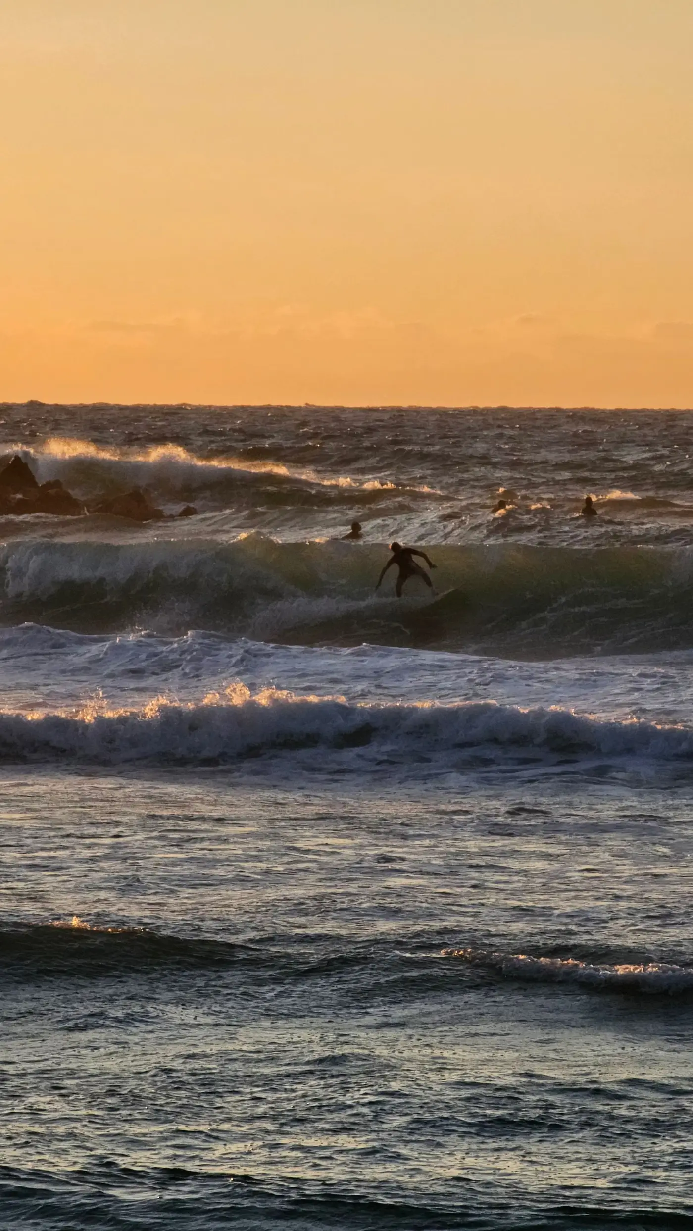 Surfista numa onda ao pôr do sol