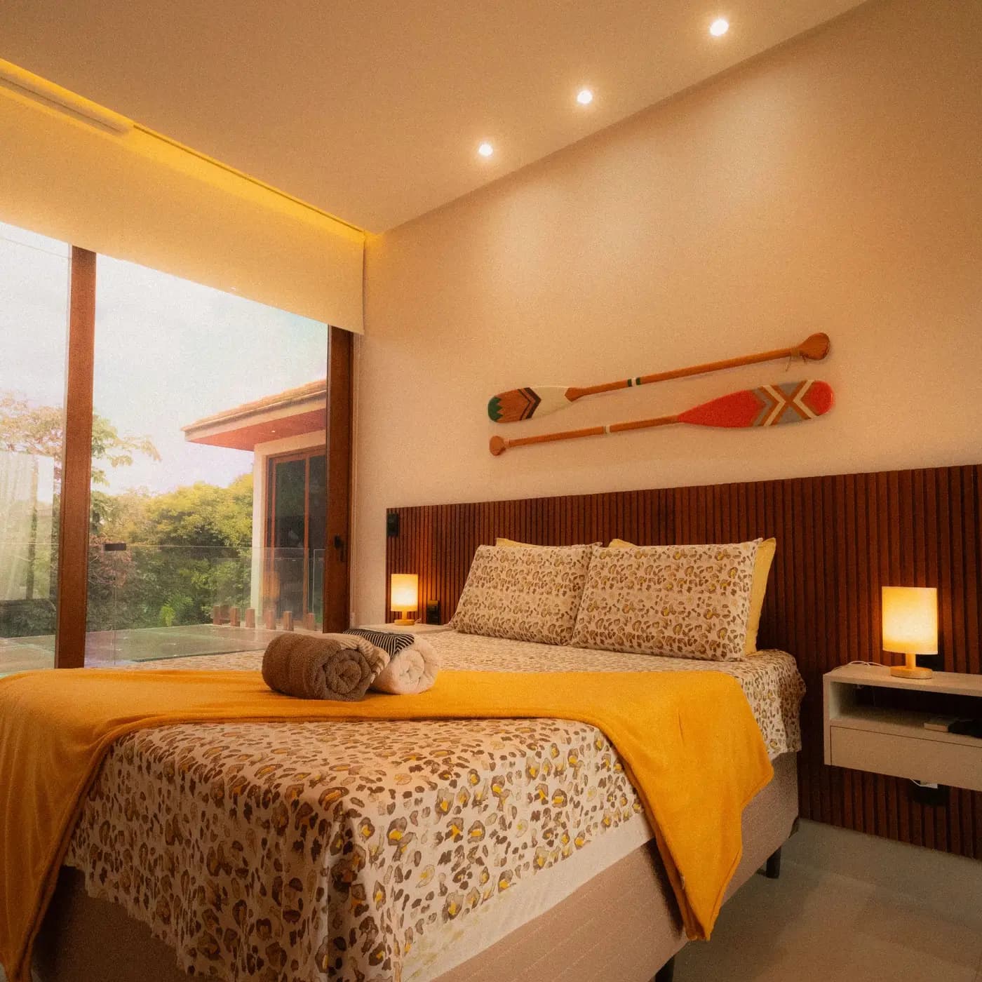Quarto com cama de casal e remos pendurados na parede